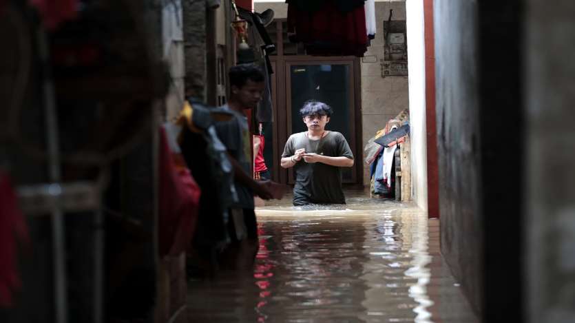 A man wades through the water at a flooded neighborhood following heavy rains in Jakarta, Indonesia.